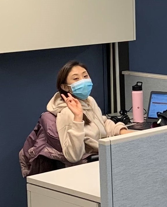 Vivian, a tutor, in a mask, sitting at her desk and gesturing